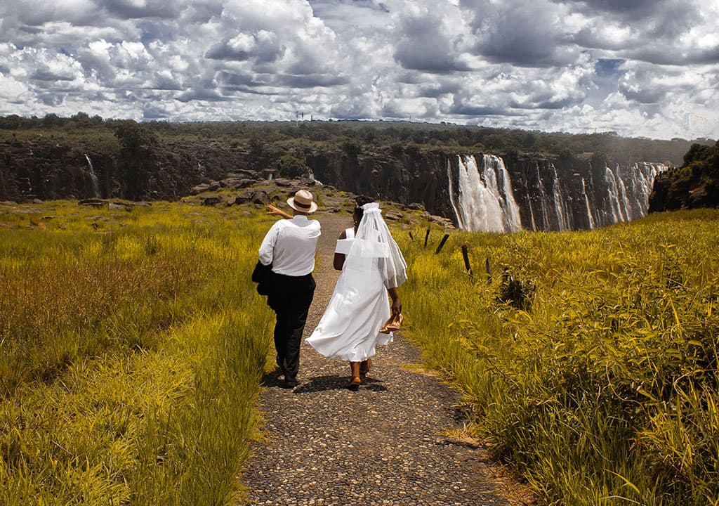 A couple walking hand in hand beside Victoria Falls
